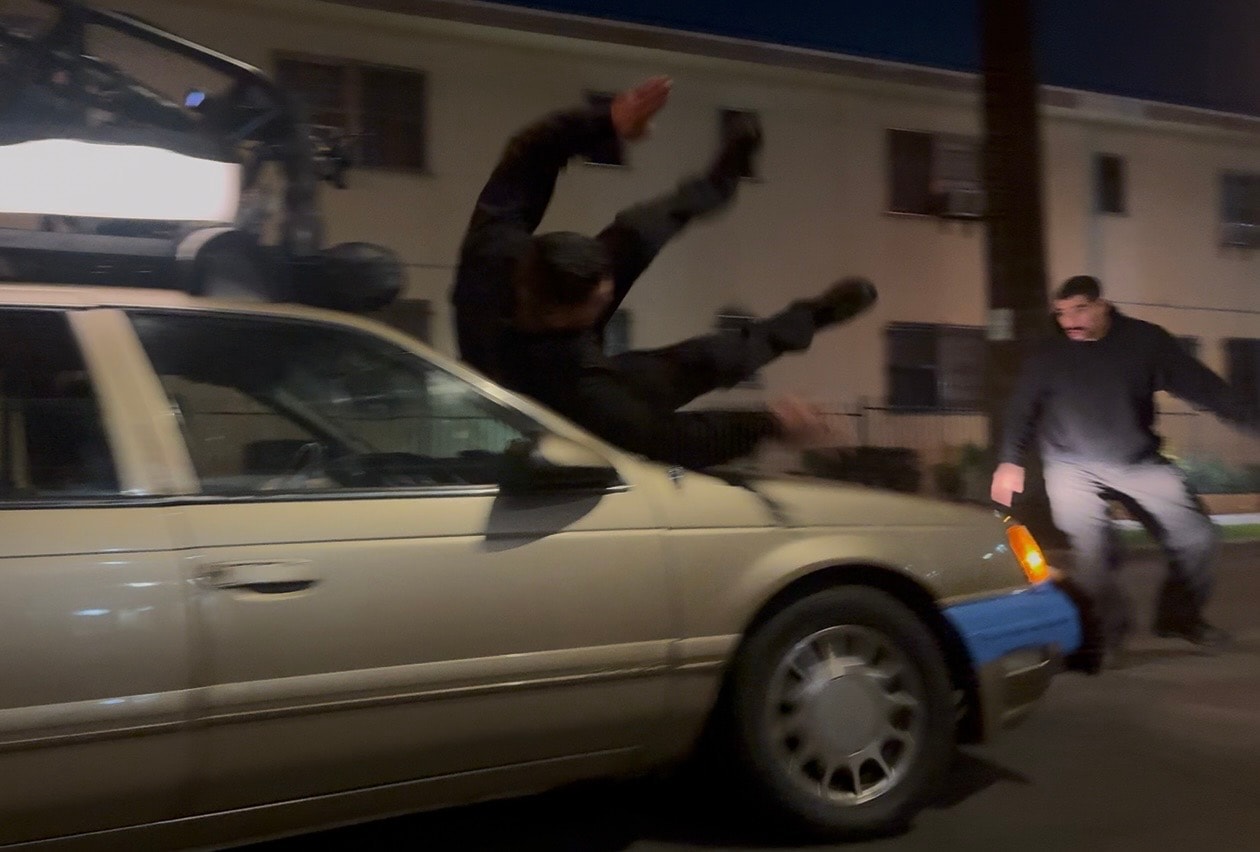 Stunt performer flying over moving car at night